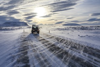 Off-road vehicle driving on icy and snowy road, storm, backlight, Myvatn, Iceland, Europe