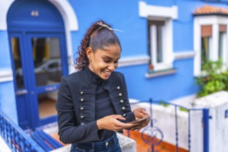 Happy and beauty african american woman using phone in a colorful street