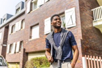 Proud african young businessman with casual clothes carrying laptop looking away standing in the