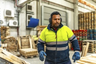 Man caucasian worker with dirty reflective clothes working in a recycling plant arranging pallets