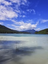 A clear lake with calm, blue water surrounded by mountains under a cloudy sky, Walchensee, Kochel