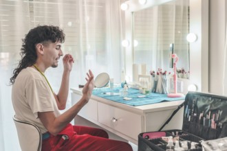 Young male makeup artist applying foundation in front of a mirror at a professional beauty salon,