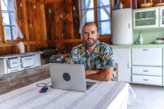 Digital nomad working on laptop in a cozy wooden cabin, embracing freedom and flexibility of remote