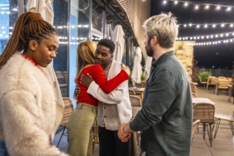 Multiracial friends saying goodbye after a dinner on a terrace at night