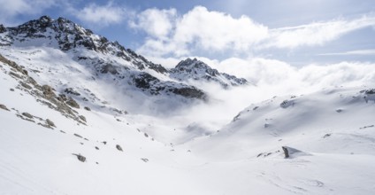 Atmospheric clouds in a wintry mountain landscape, ascent to Porta d'Es-cha, Bündner Haute Route