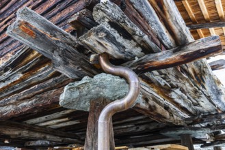 Old weathered hay barn with wooden support, stone slab and copper pipe, Chandolin, Val d'Anniviers,