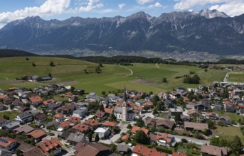 Drone shot, view of village with parish church and Karwendel mountains, Rinn, Tyrol, Austria,