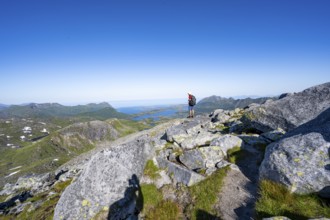 View of mountains and fjord landscape, mountaineer at the summit of Rundfjellet, Svolvaer,