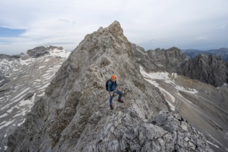 Mountaineer with helmet on a narrow rocky ridge, crossing the Jubiläumsgrat, Wetterstein range,