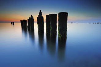 Stone pyramids on old groynes with algae in the water on the beach of the Baltic Sea, long exposure