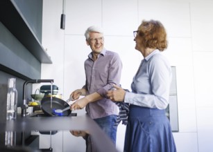 Symbolic photo. An elderly couple stand in the kitchen and do the washing up together. Berlin, 13