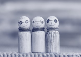 Three small funny wooden cones, monochrome in front of a painted background, North