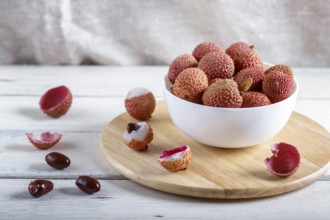 Lychee in a white plate on a white wooden background, close up