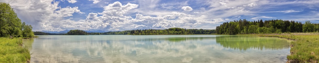 Lake with clear water surface, cloudy sky and surrounding green nature, Easter Lakes
