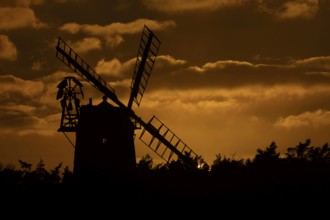 Windmill silhouette at sunset with a red sky and clouds behind, Cley-next-to-the-sea, Norfolk,
