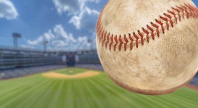 Baseball flying through the air with stadium in the background