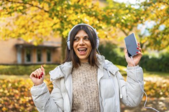 Frontal view of a cute beauty caucasian woman listening to music and dancing in a park enjoying