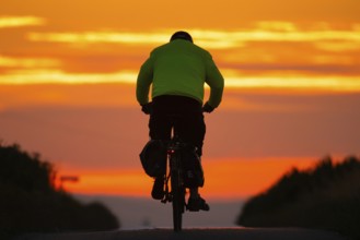 A cyclist rides towards the sunrise, Frankfurt am Main, Hesse, Germany, Europe