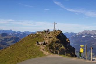 Hiking on the Kitzbüheler Horn in Tyrol: summit cross with a view on a pre-summit just below the