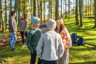 Caucasian family with three teens having fun during a camping in a green alpine forest