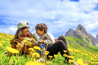 Mother and son relaxing in a dandelion field, enjoying the breathtaking view of the seceda
