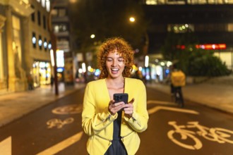 Casual beauty woman with curly hair expressing surprise while using smartphone in the city at night