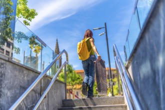 Low angle view photo of the rear view of a young woman with casual denim clothes and a bag carrying