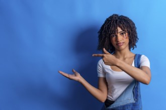 Young woman pointing her finger to the side and showing something with her open hand on a vibrant