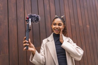 Cute and beauty african american woman recording vlog in the city next to a wooden wall