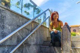 Cool asian young woman holding a skateboard sitting on stairs in the city in summer