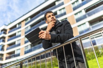 Low angle view potrait of a caucasian pensive businessman in casual winter clothes using digital