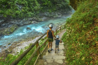 Tourists wearing helmets are enjoying a summer walk along the stunning turquoise radovna river