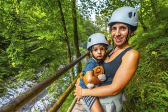 Mother holding her son while wearing helmets and enjoying the stunning view of vintgar gorge near