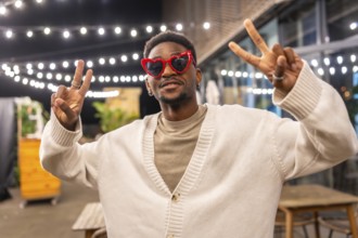 Cool african man gesturing success smiling at camera in a bar terrace at night