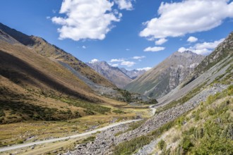 Gravel track in a valley, picturesque mountain landscape with white mountain peaks, Tian Shan