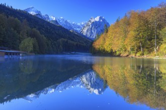 Mountains reflected in lake, fog, morning light, autumn colours, Riessersee, Waxensteine behind,