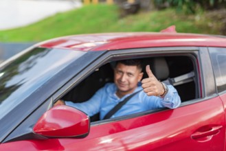 Smiling driver in his car giving a thumbs up. Male driver showing thumbs up while driving