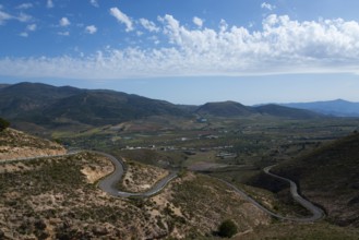 Mountain landscape with serpentine road in green valley under blue sky with clouds, road to Mirador