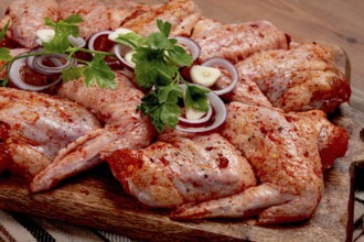 Chicken wings, marinated and laid out on a wooden platter, ready for cooking, grilling or baking,