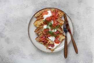 Delicious pancakes with salmon and sour cream, breakfast, on a plate, rustic style, with cutlery