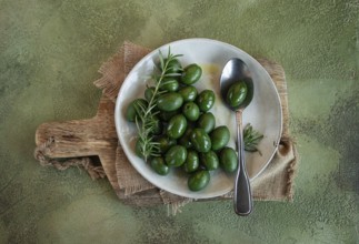 Chalkidiki olives, classic Greek green olive, on a plate, with a spoon, top view, no people