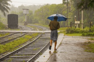 Sinhalese with umbrella in heavy rain, monsoon, railway station in Kalawewa, Sri Lanka, Ceylon,