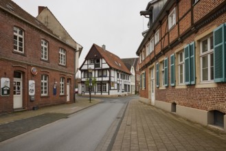 Historic brick houses with white windows and shutters and a small half-timbered house in Warendorf,