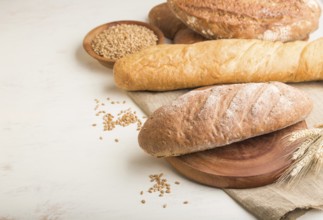 Different kinds of fresh baked bread on a white wooden background. side view, close up, copy space