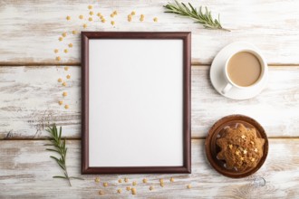 Brown wooden frame mockup with cup of coffee and cake on white wooden background. Blank, top view,