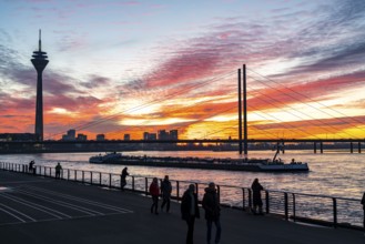 Winter sunset on the Rhine near Düsseldorf, riverside promenade at the old town, Rhine Tower, cargo