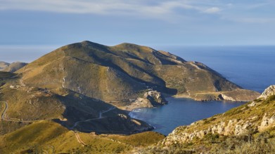 Sunny coastal road winding along a mountainous landscape overlooking the sea, southern tip, Mani