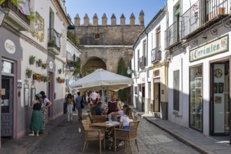 Lively old town street with street café, surrounded by historic buildings and flowers, Cordoba