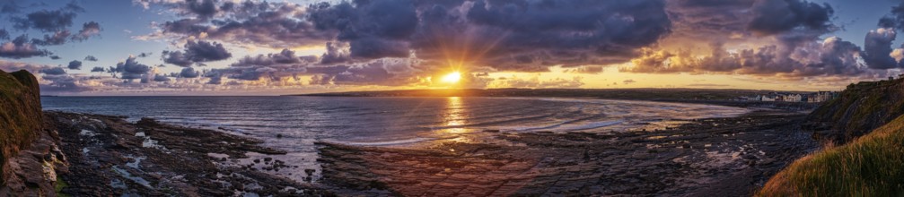 Impressive sunset over the sea, bright orange-red sky, rocks in the foreground, Lahinch Beach