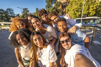 Multiracial group of happy young friends taking selfie together at street during sunset